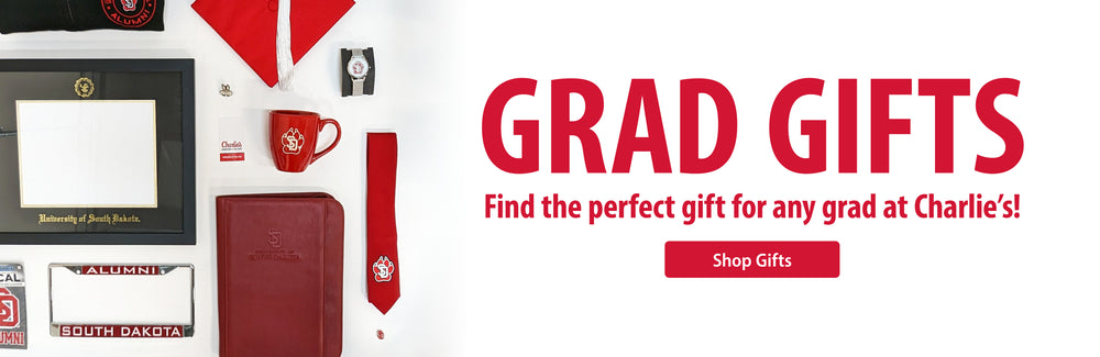 Flat lay image of diploma frame, red graduation cap with white tassel, watch, red tie with SD Paw logo, red padfolio, red mug, alumni license plate frame and graphic to the right that says, 'GRAD GIFTS Find the perfect gift for any grad at Charlie's! Shop Gifts.'