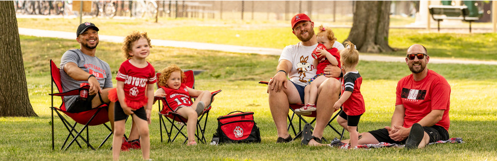 Three dads and four kids sitting in the park in lawn chairs