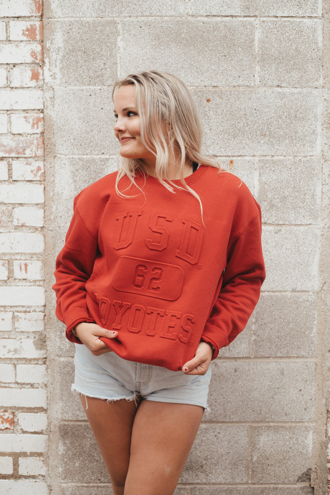 Red sweatshirt with embossed lettering that says, 'USD COYOTES 62' on chest
