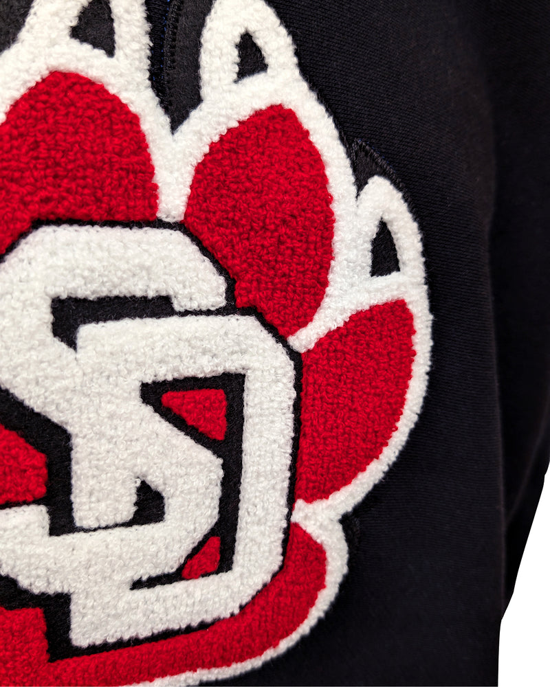 Close-up of chenille paw logo on black crew. 