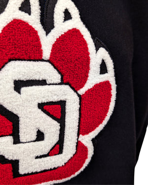 Close-up of chenille paw logo on black crew. 