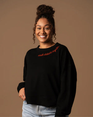 Person wearing a black sweatshirt with red text at the neckline, 'south dakota coyotes.'