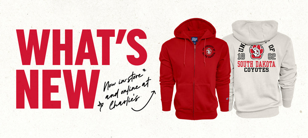 Graphic with paper textured background and red text to the left side, 'WHAT'S NEW,' with smaller black handwriting text, 'Now in-store and online at Charlie's,' with an arrow pointing to red fill zip jacket and the back of an oatmeal full zip with large screenprint of SD Paw log and text 'UNIVERSITY OF SOUTH DAKOTA COYOTES 1862.'