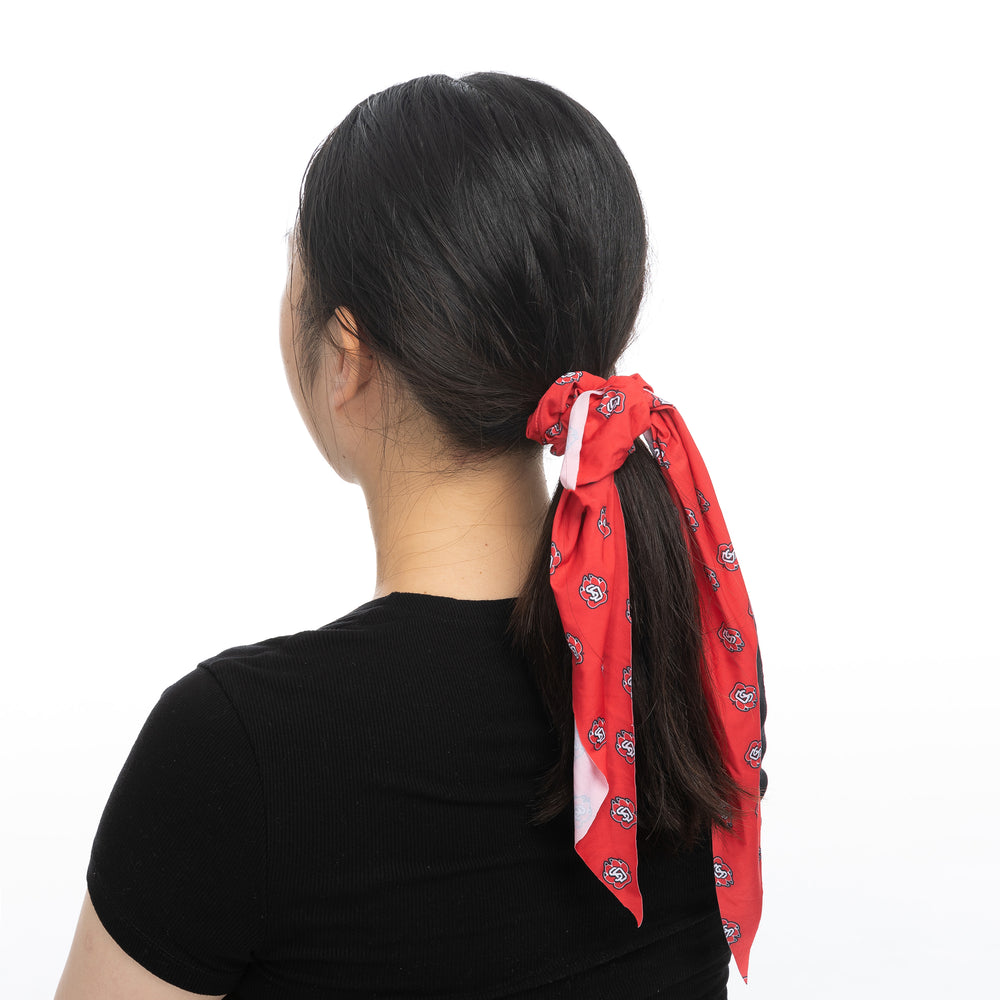 Woman wearing red scrunchie scarf with SD Paw logo print in pony tail,