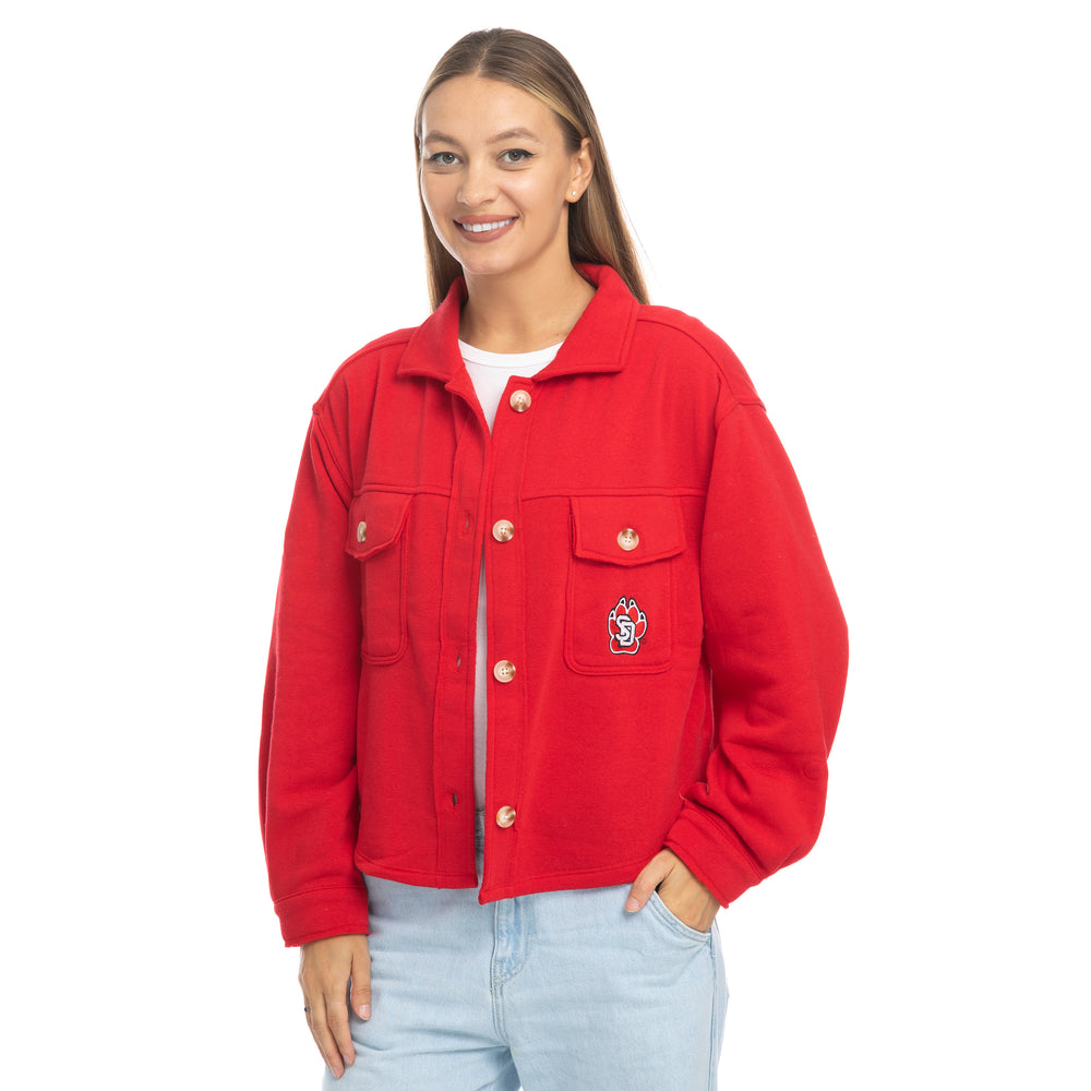 Young woman wearing jeans and the red shacket that has large buttons and the SD Paw logo on the upper jacket pocket.