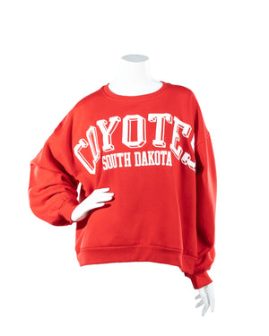 Red oversized women's crew with white block letter, 'COYOTES SOUTH DAKOTA,' across chest.