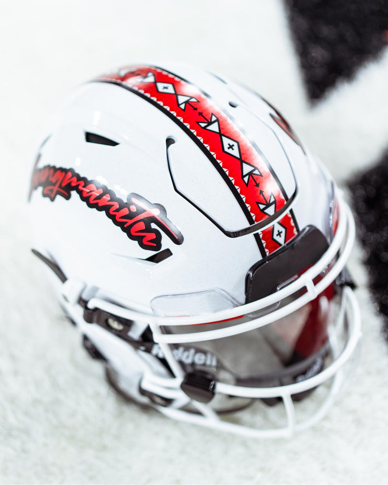 Mockup of white mini football helmet with with word 'Sungmanitu' on the side and a red stripe with Native American symbols on the top. 