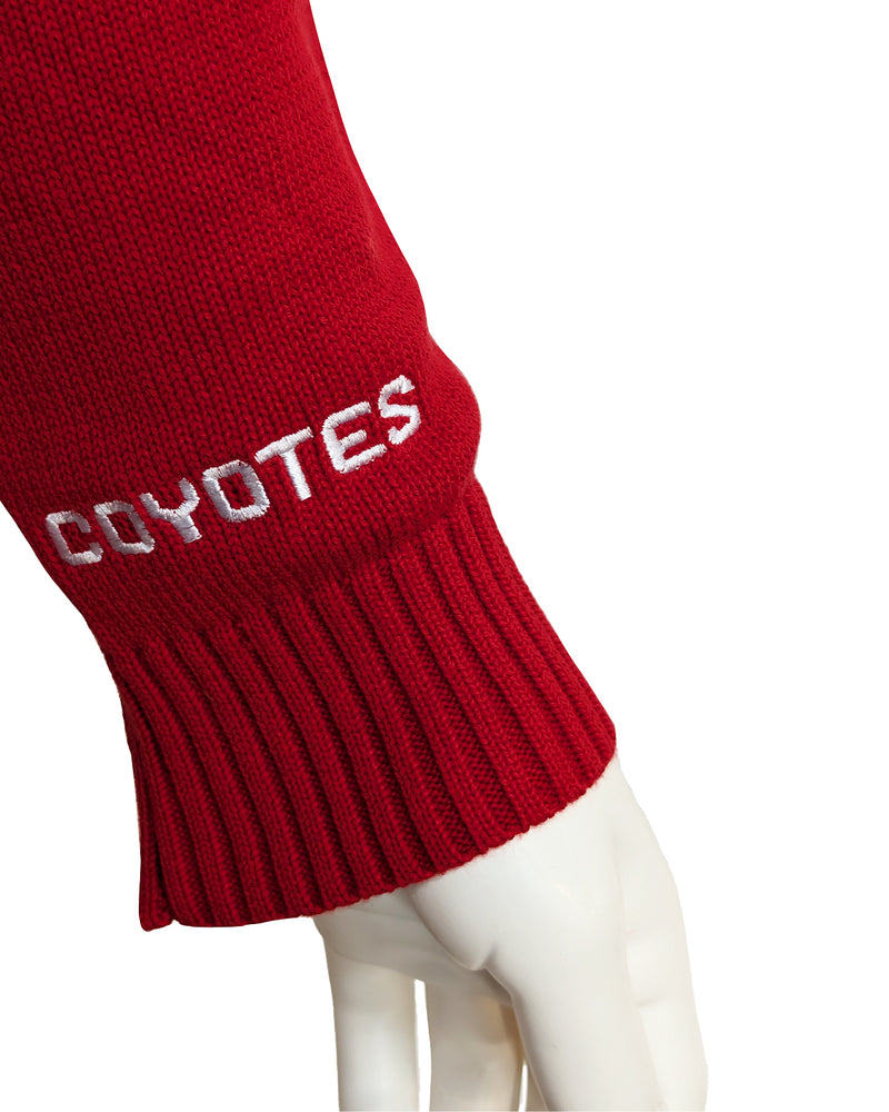 Close up of white embroidered, 'COYOTES,' on sleeve of red sweater.