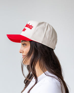 Other side view of person wearing a cream hat red embroidered script 'South Dakota Coyotes' and a red bill. 