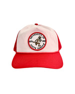 Red trucker style hat with white front panel with a round patch featuring a running vintage Charlie in the middle and text around the outside, 'UNIVERSITY OF SOUTH DAKOTA EST. 1862.'