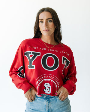 Red long sleeve with black and white text, 'COYOTES' across arms and chest and text on torso that says, 'FIGHT FOR SOUTH DAKOTA' and 'UNIVERSITY OF SOUTH DAKOTA' in white.