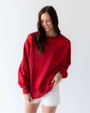 Woman wearing a red crew with tonal SD Paw logos sporadically covering garment.