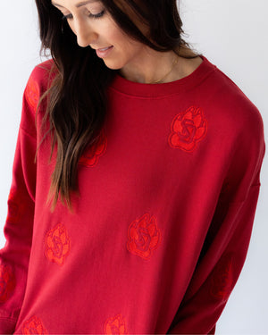 Close-up of woman wearing a red crew with tonal SD Paw logos sporadically covering garment.