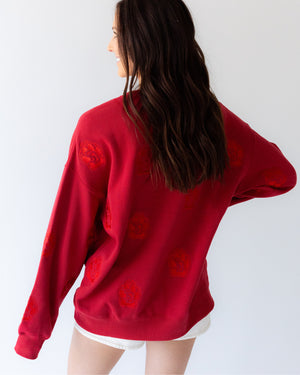 Back of woman wearing a red crew with tonal SD Paw logos sporadically covering garment.
