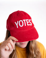 Red corduroy hat with puffy white, 'YOTES,' embroidered across front. 