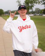 Person wearing a white hoodie with 'Yotes' script in red text standing outdoors.