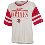 White tee with red sleeves with white stripes and graphic across chest in red a small flag with, 'USD,' and large text below, 'COYOTES,' with the SD logo smaller below.